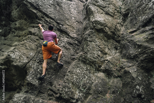 Young man climbing on stone rock