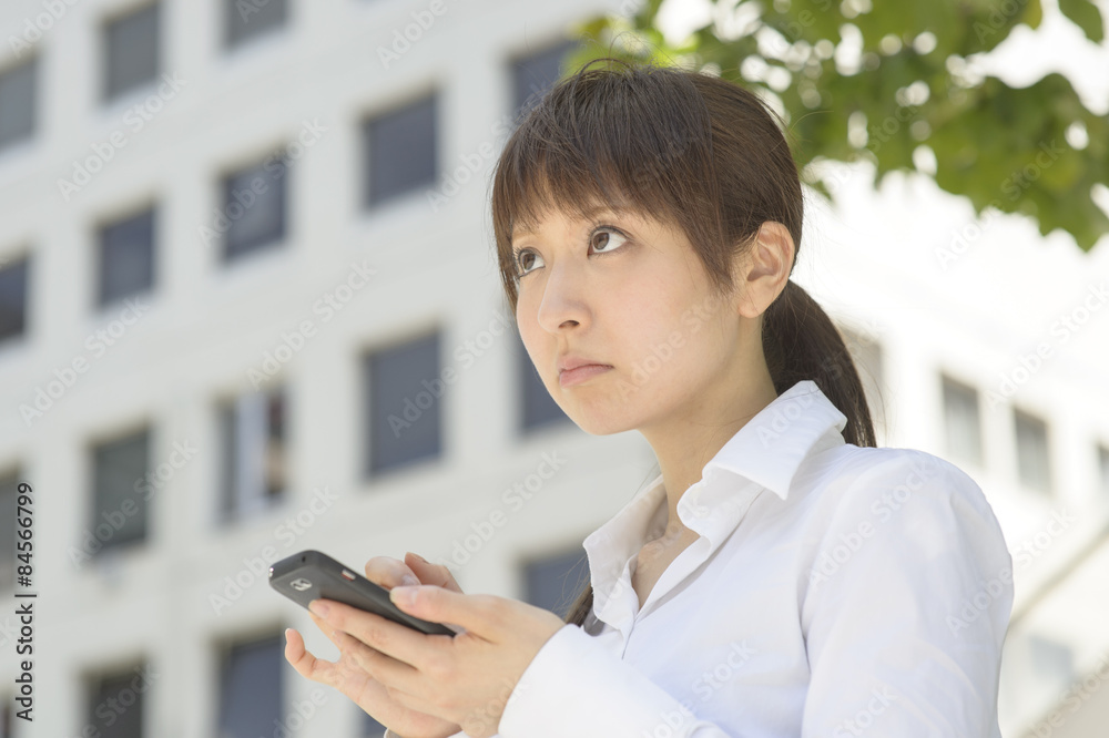 スマートフォンを見てがっかりする若い日本人女性 スマートフォンを見てがっかりする若い日本人女性