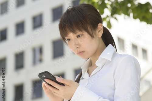 スマートフォンを見てがっかりする若い日本人女性