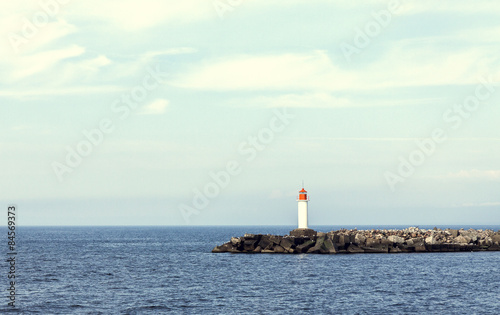 Vintage colorized picture of white lighthouse and stone pier 