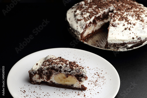 Banana and chocolate cake on porcelain plate. Dark background
