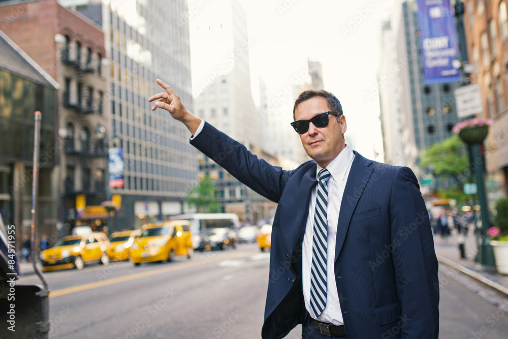 Fototapeta premium Businessman calling a taxi in Manhattan on the street. New York