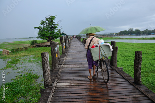 Old man bring bicycle cross over lake at U Bein Bridge