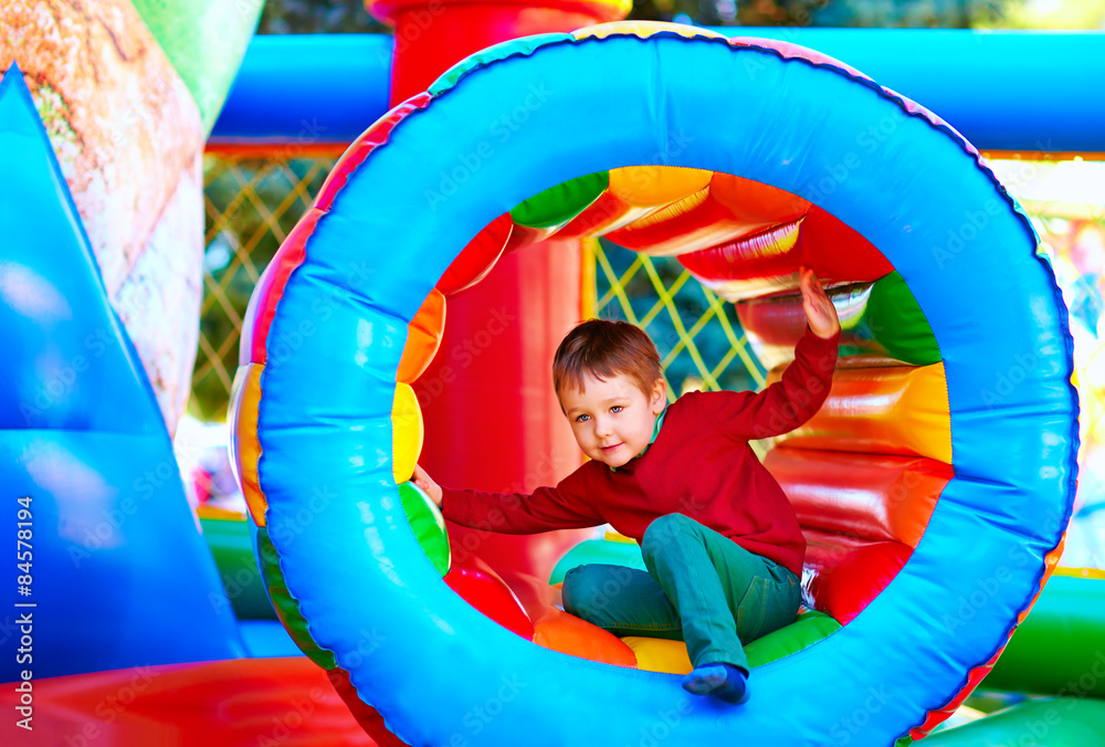 cute happy kid, boy playing in inflatable attraction on playground ...