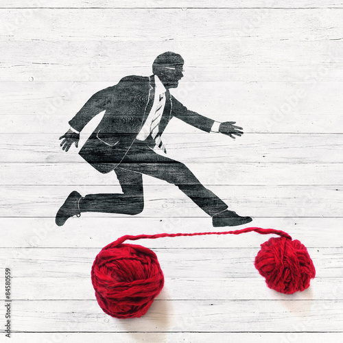 Businessman jumping over red thread