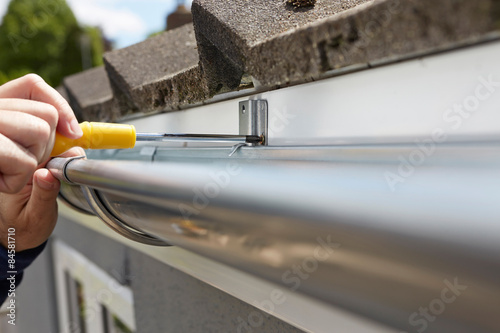Close Up Of Man Replacing Guttering On Exterior Of House photo
