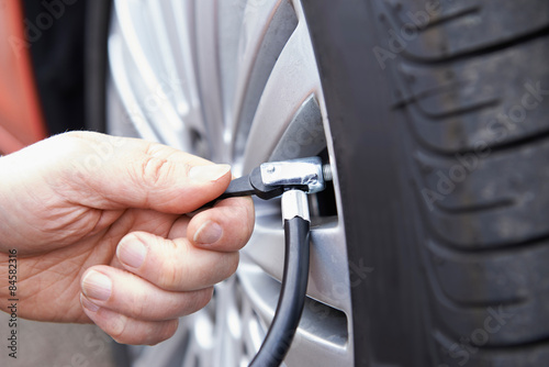 Close Up Of Man Inflating Car Tyre With Air Pressure Line © highwaystarz