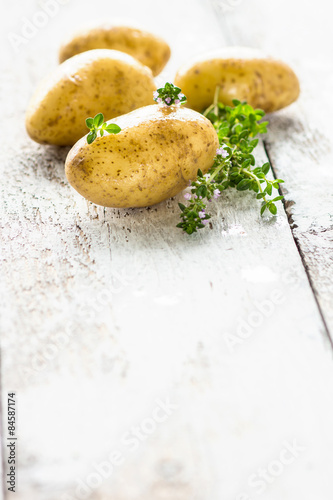 Fresh young potatoes on a wooden background with herbs