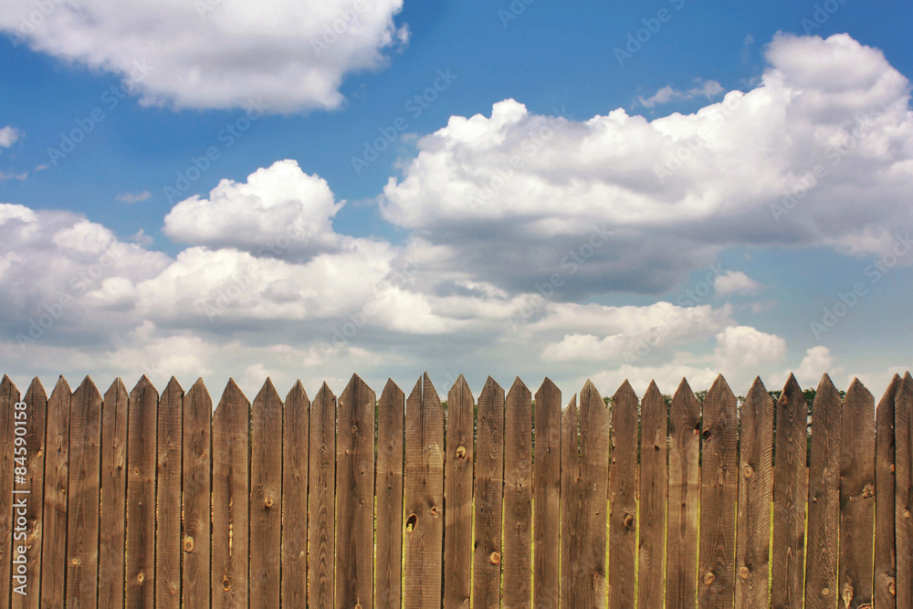 Obraz premium Dark old wood fence is against the blue sky