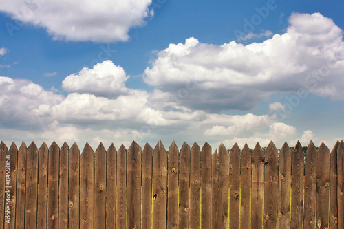 Dark old wood fence is against the blue sky