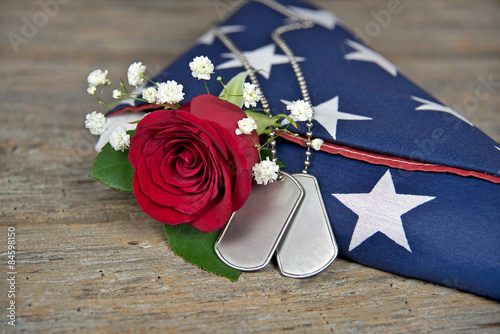 dog tags and red rose on folded American flag