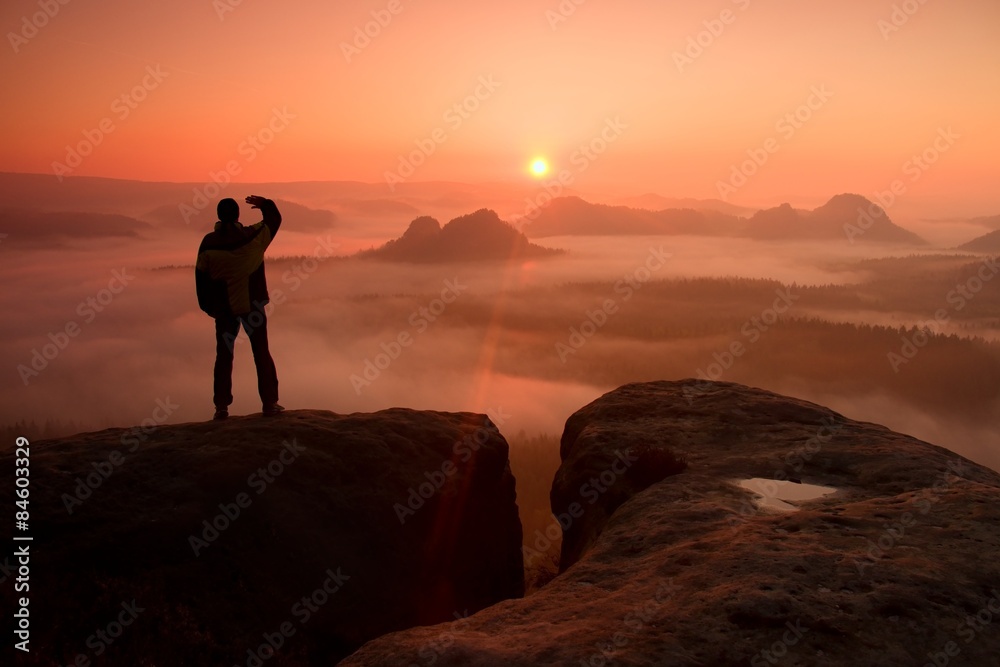 Happy hiker is standing on the peak of  rock empires park and watching over the misty and foggy morning valley to Sun. Beautiful moment the miracle of nature