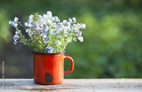 Forget me not flowers in a jar on wooden background