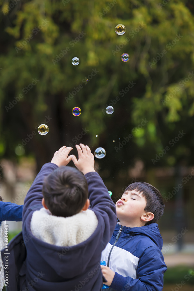 Niños jugando en el parque con pompas de jabón Stock Photo