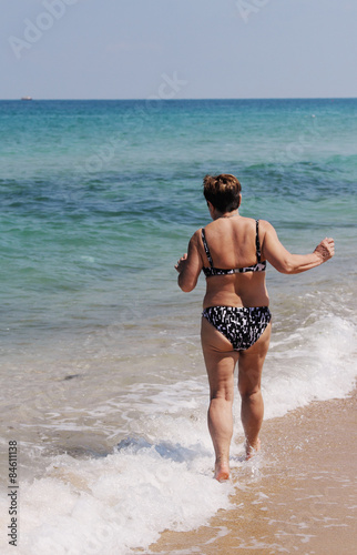 senior woman is going to swim in the sea © dubova