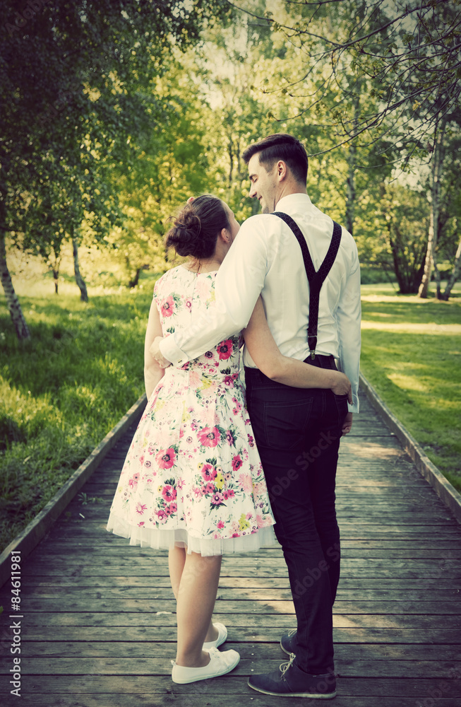 Young couple embrace while standing on wooden path Young couple embrace while standing on wooden path