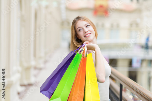 A happy smiling young lady with a lot of colourful shopping bags from the fancy shops. © ImageFlow