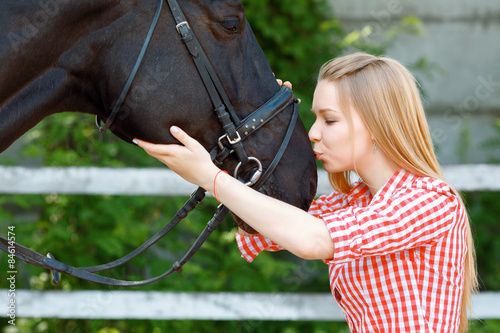 Vivacious young girl kissing the horse