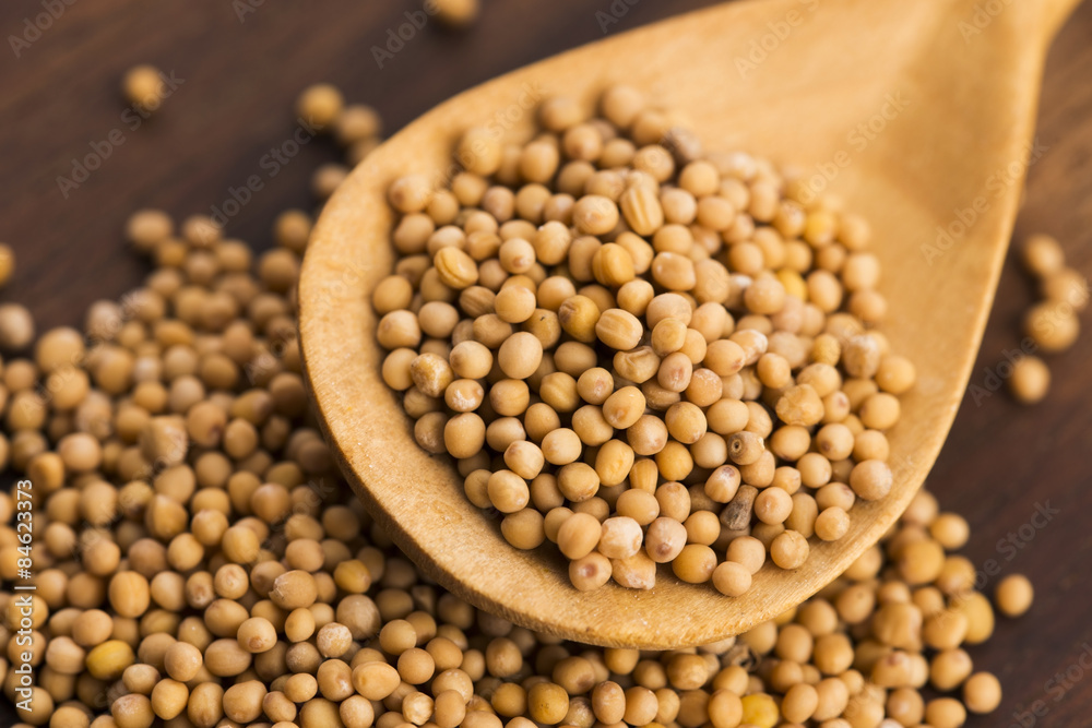 Spicy mustard seeds in a wooden background