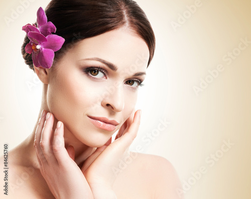Beautiful face of a young and healthy girl with an orchid flower
