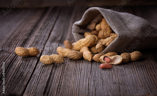 peanuts in a miniature burlap bag on wooden surface photo