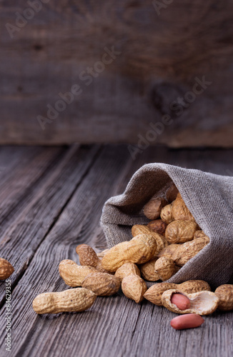 peanuts in a miniature burlap bag on wooden surface