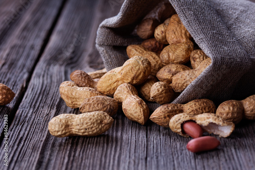 peanuts in a miniature burlap bag on wooden surface