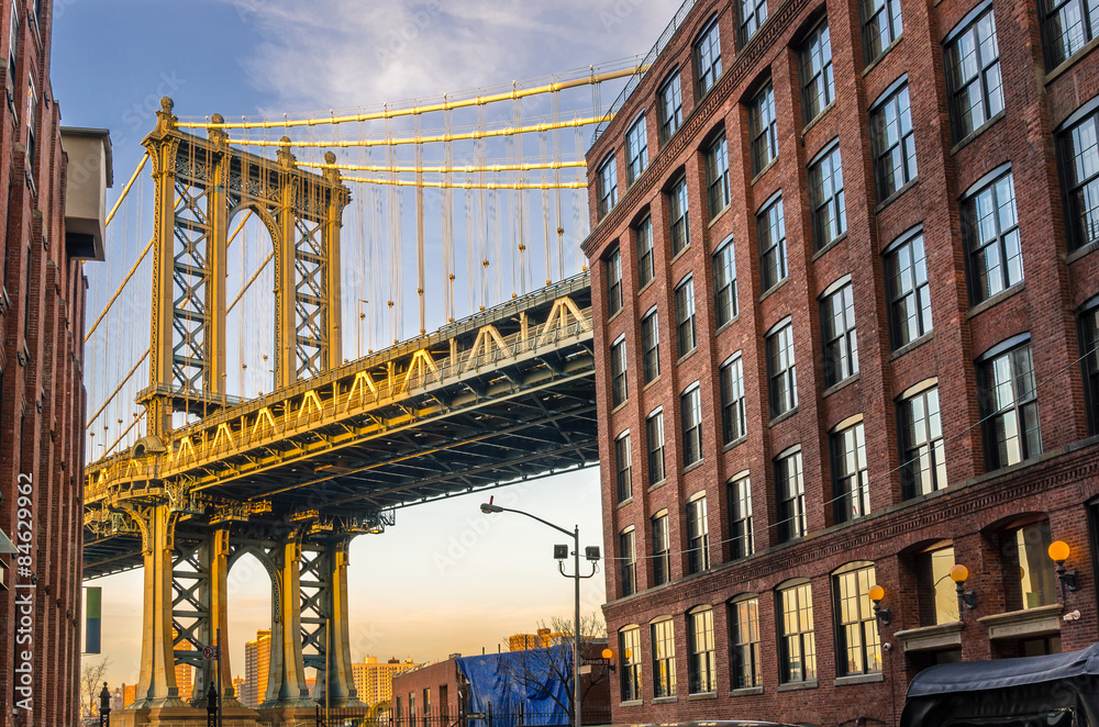 Fototapeta premium Manhattan most między ceglanymi budynkami przy zmierzchem