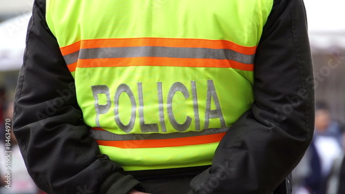Anonymous police officers from the back wearing yellow fluorescent vests marked with the word police in the Spanish language.