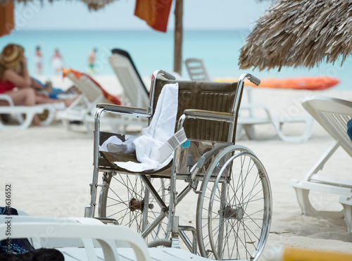 Closeup view of empty wheelchair standing on tropical beach against ocean background