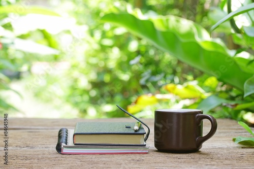 Notebook and coffee in brown cup on wooden table