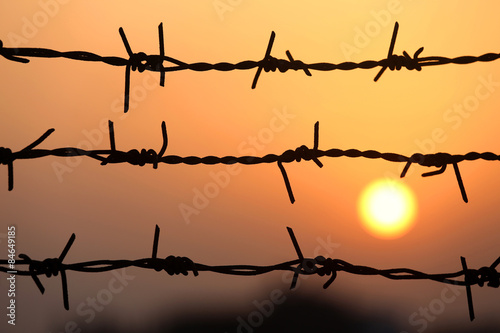 Obraz na płótnie Setting sun behind barbed wire
