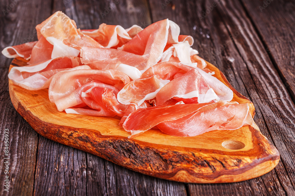 Prosciutto served on a olive cutting board