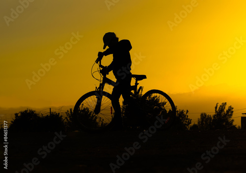Fototapeta Naklejka Na Ścianę i Meble -  Silhouette of a boy with a bicycle against the sky at sunset,