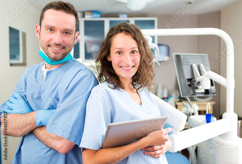 Portrait of a young attractive dentist and his assistant in his