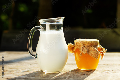 a jug of milk and honey on wooden table