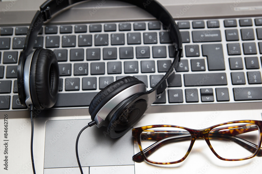 Headphones on laptop with eyeglasses Headphones on laptop with eyeglasses