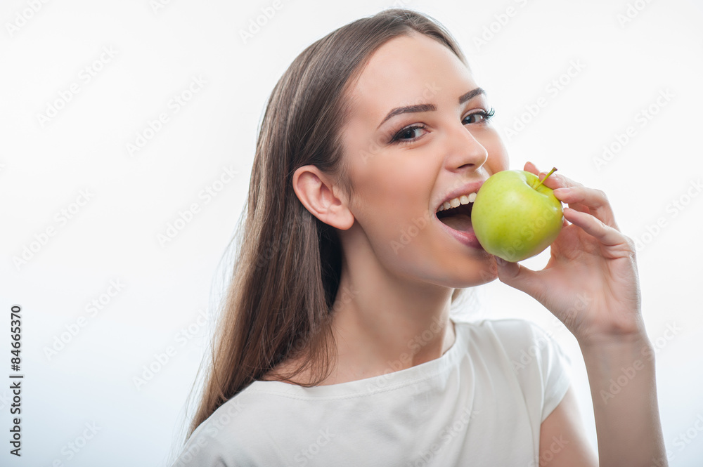 Beautiful healthy woman is eating green fruit Beautiful healthy woman is eating green fruit
