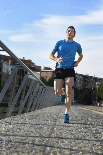 healthy sport man with athletic legs running in urban city park 