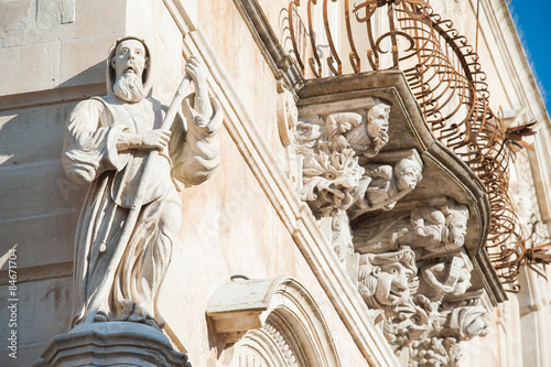 The baroque statue of St. Francis of Paola sculpted at the corner of Cosentini palace in Ragusa Ibla with some mascarons under its balconies photo