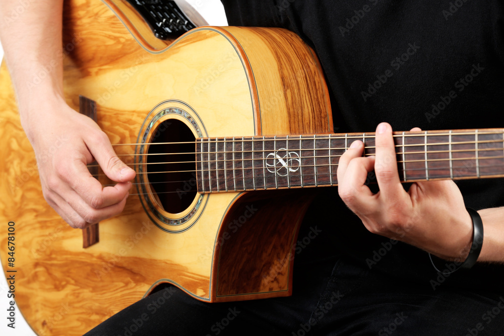 Fototapeta premium Young man playing on acoustic guitar close up