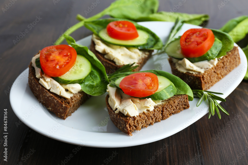 Delicious sandwiches with vegetables and greens on plate close up