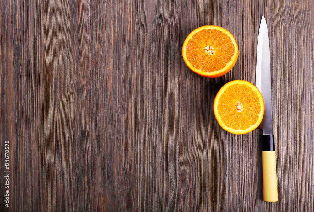 Halves of orange with knife on wooden background Halves of orange with knife on wooden background