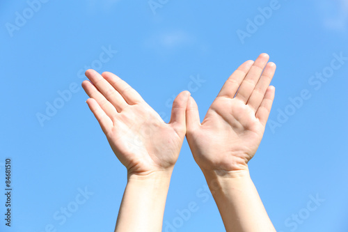 Female hands over blue sky background