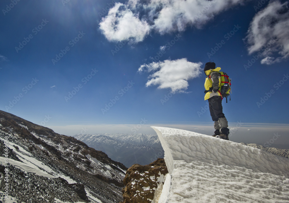 man standing on a snow cornice in mountain sunrise