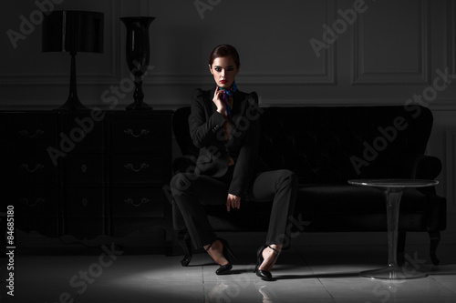 fashionable woman in black suit in dark minimalistic interior