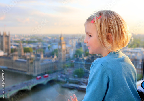 Family with young children enjoying trip to UK. Kids looking through the window of London Eye wheel. Beautiful view on London's southern part: cityscape, Westminster Abbey, Big Ben and Thames river