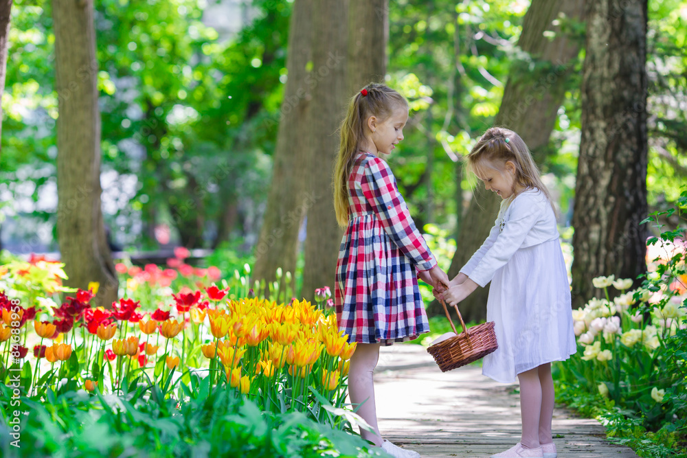 Little adorable girls walking in lush garden of tulips