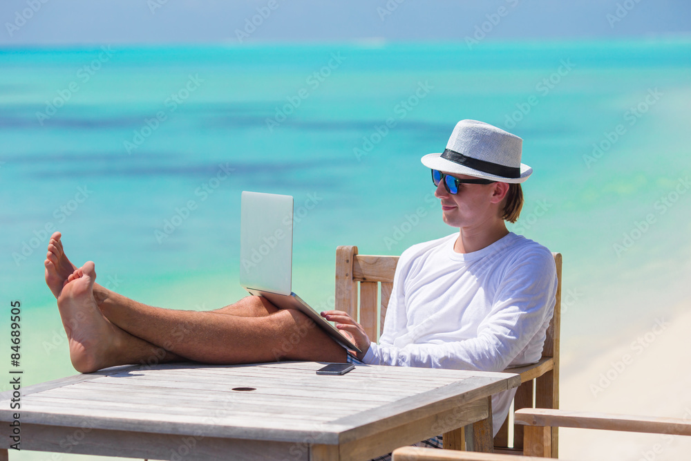 Young man with tablet computer on tropical beach