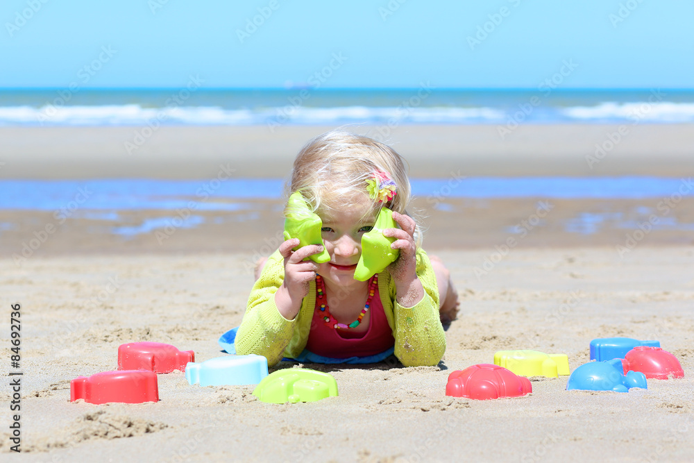 Happy little child on the beach. Cute toddler girl enjoying summer vacation at the North sea building sand castles and playing with plastic toys. Happy little child on the beach. Cute toddler girl enjoying summer vacation at the North sea building sand castles and playing with plastic toys.